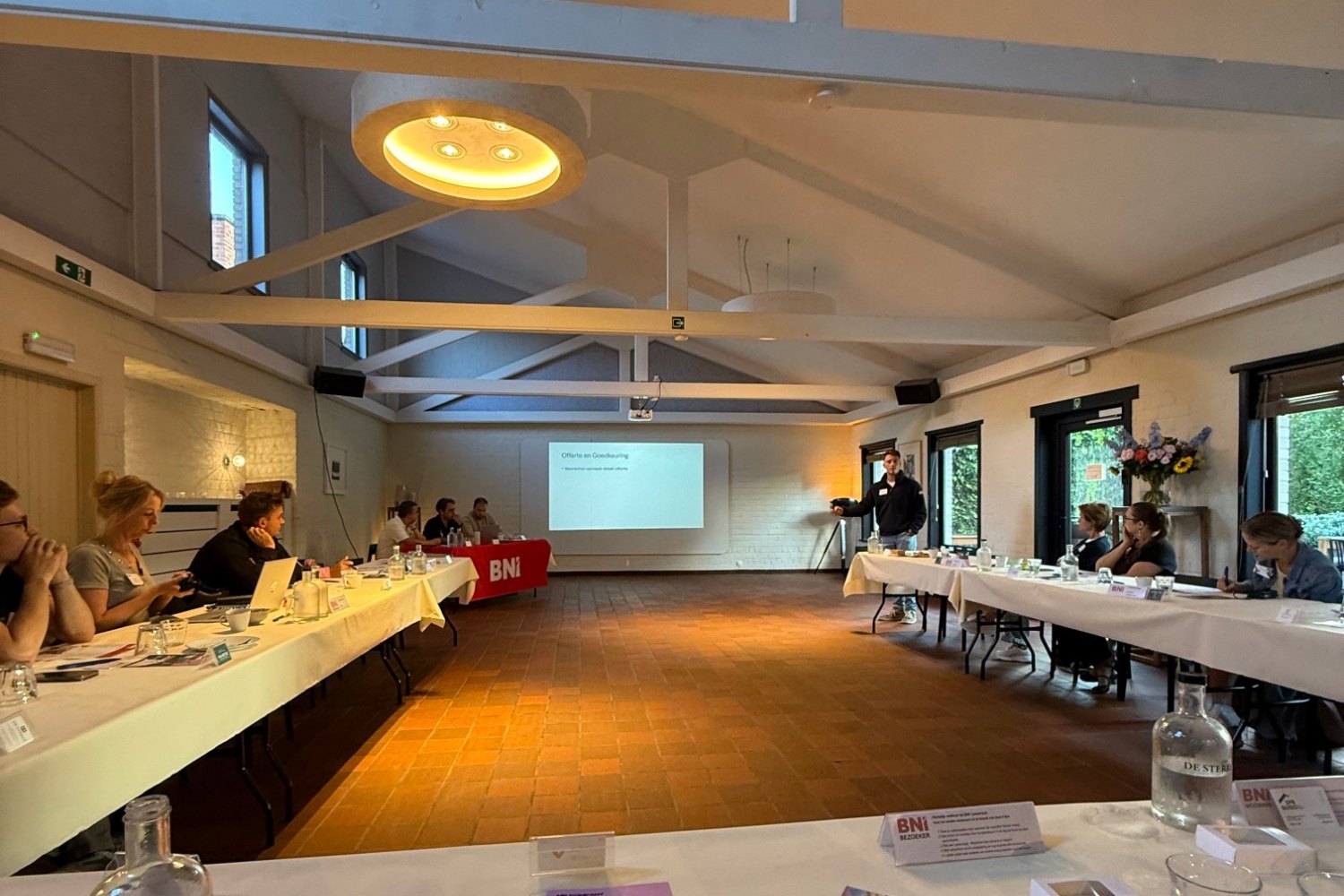 Seminarie in de vergaderzaal van De Sterre in Deinze, met projectiescherm en tafels in U-opstelling